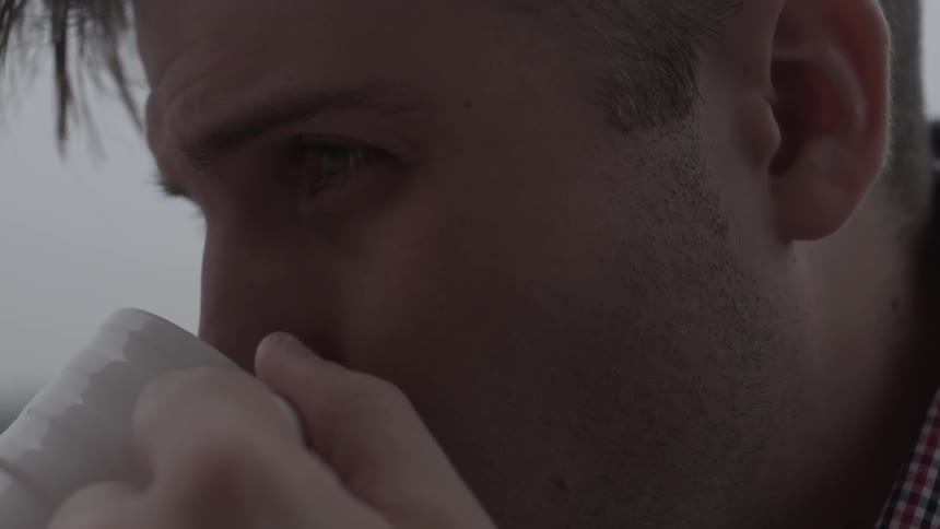 Close up of a man drinking from a white mug