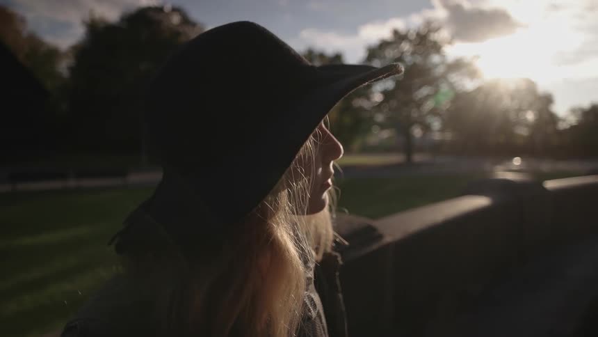 A woman wearing a cowboy hat peers at the sun
