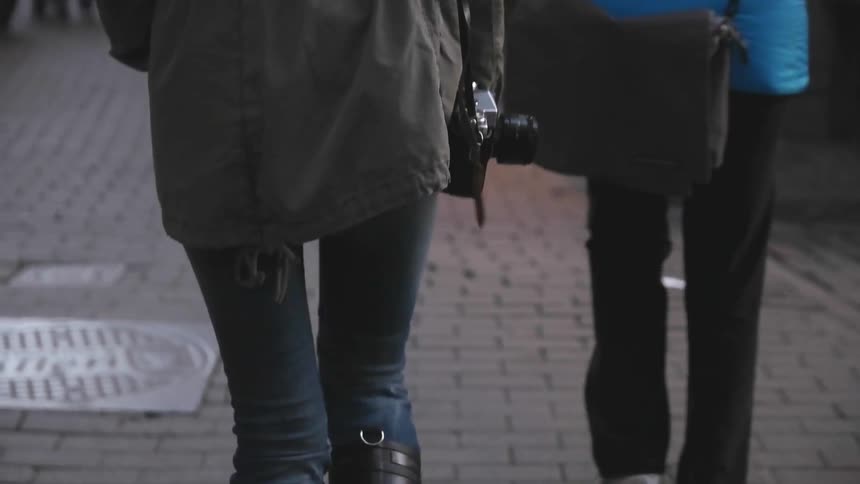 Woman with camera and other people walking down a sidewalk