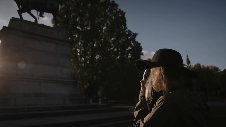 A woman photographs a statue on a sunny day