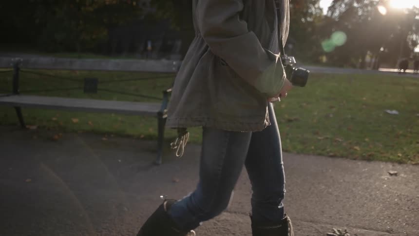A photographer walking past benches on a park path