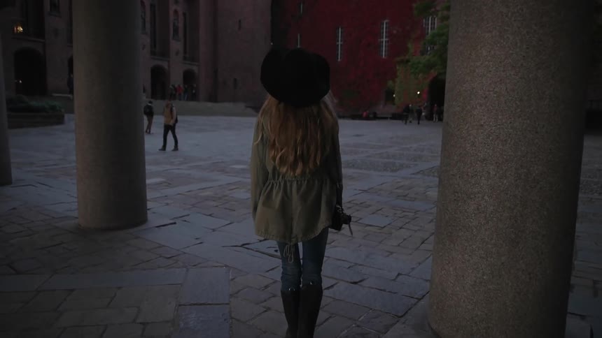 A woman walks into a square while holding a camera