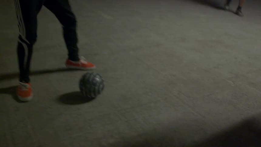 Group of friends play indoor soccer on a parking garage