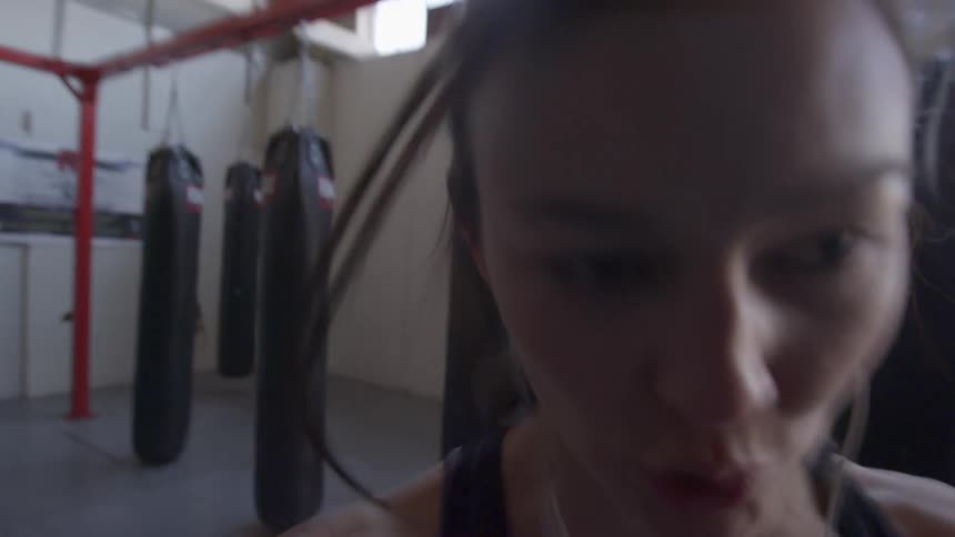 Woman with protective hand covering kicks and punches bag in gym