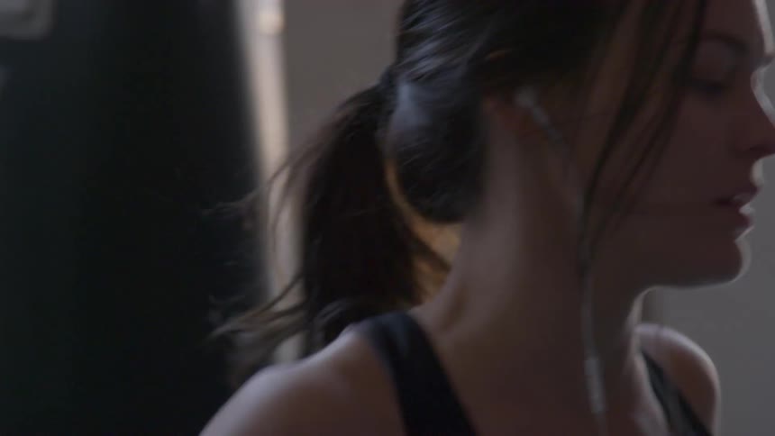 Woman puts on headphones in gym then starts punching workout