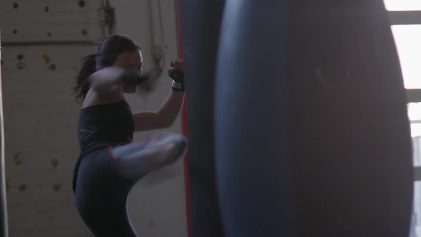 A woman kicks a punching bag