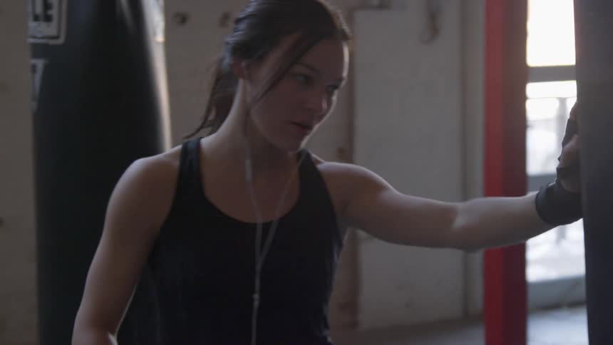 A young woman punches a punching bag