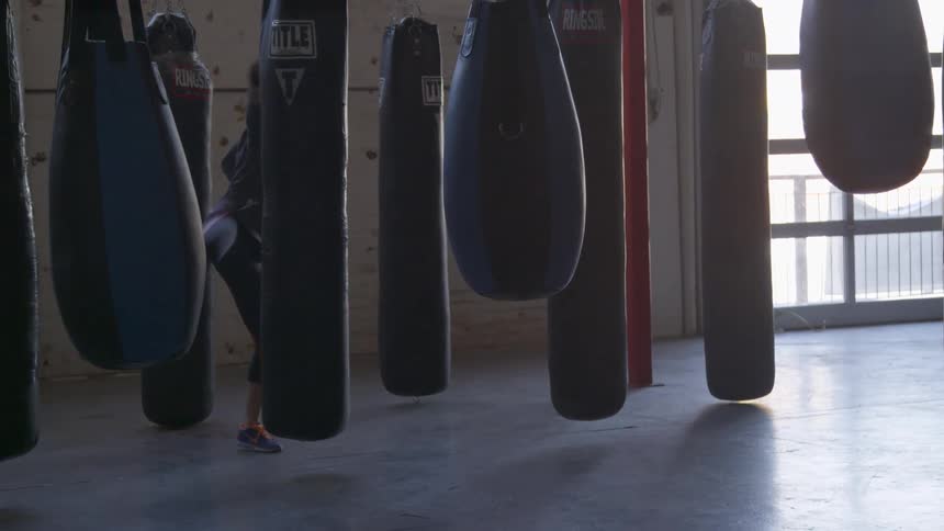 A woman is kicking a heavy bag