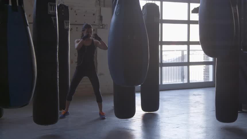 Woman kicks punching bags in a gym