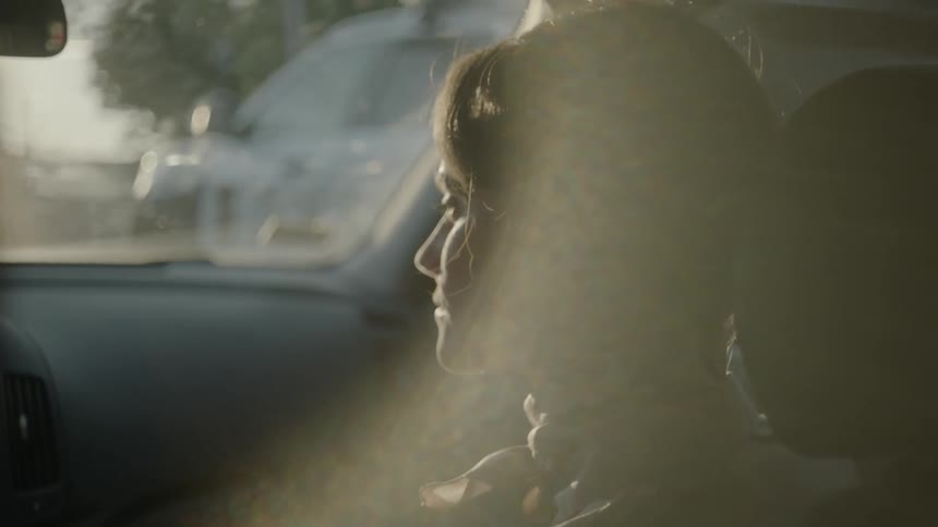 A woman sitting in the passenger seat smiles at the driver
