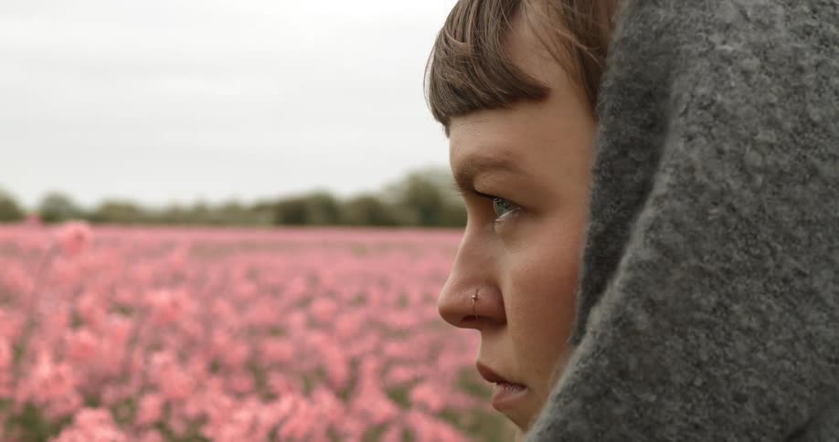 A teenager stands in field of flowers