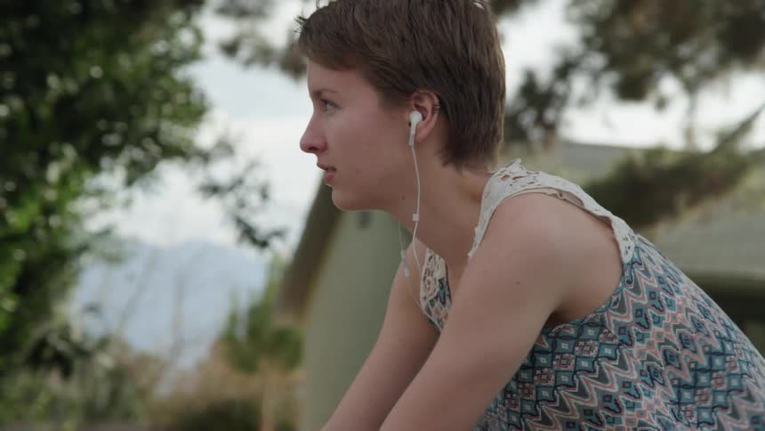 A teenager bikes through a neighborhood while listening to music