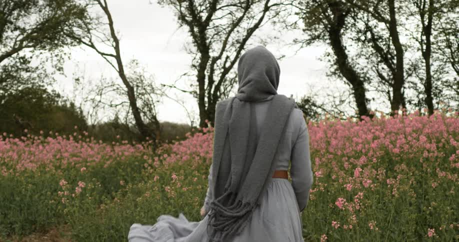 A woman is walking through a flower meadow