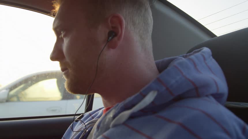 A man sits in a car with headphones in