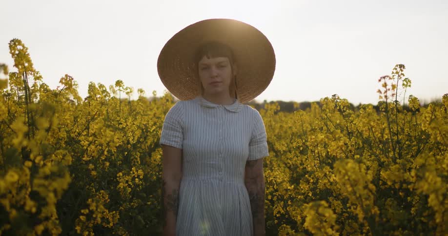 A woman touches her hat as she walks through the field