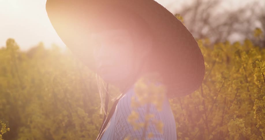 Woman stands in field of flowers under bright glaring sunshine