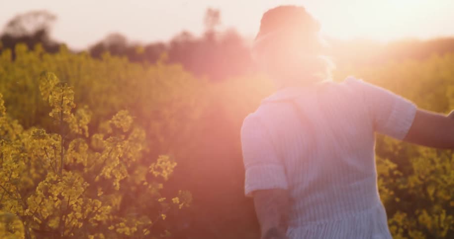 A woman is running outside holding her hat
