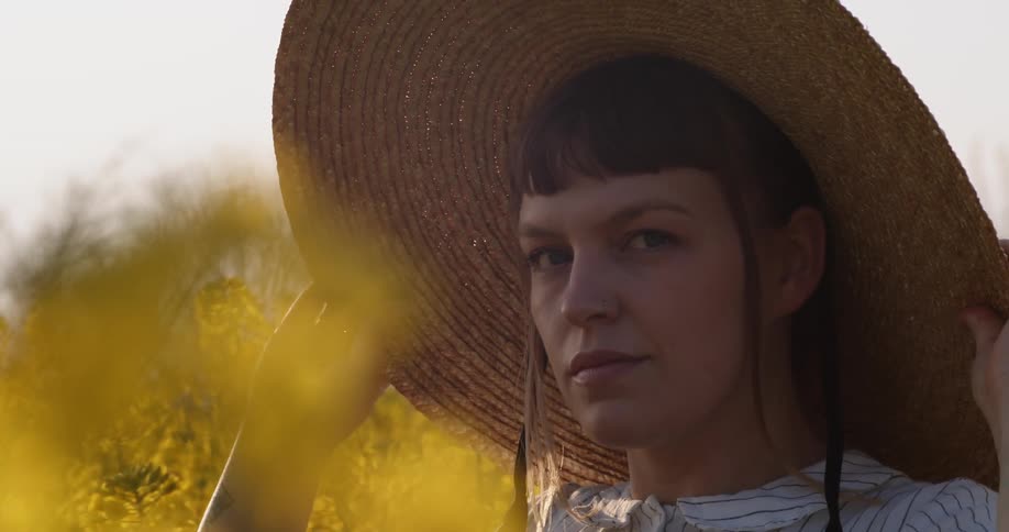 Woman wears a sun hat in a field of wild flowers at sunset
