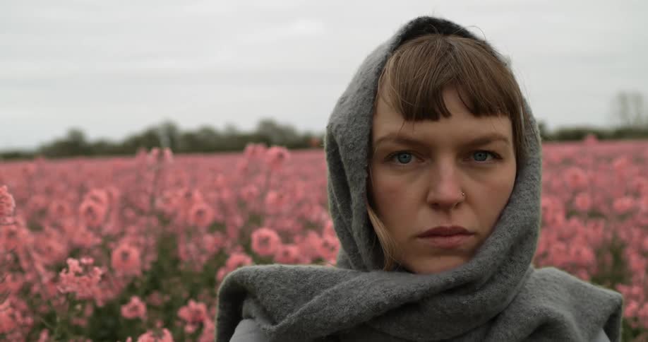 A young woman stands in a field of flowers