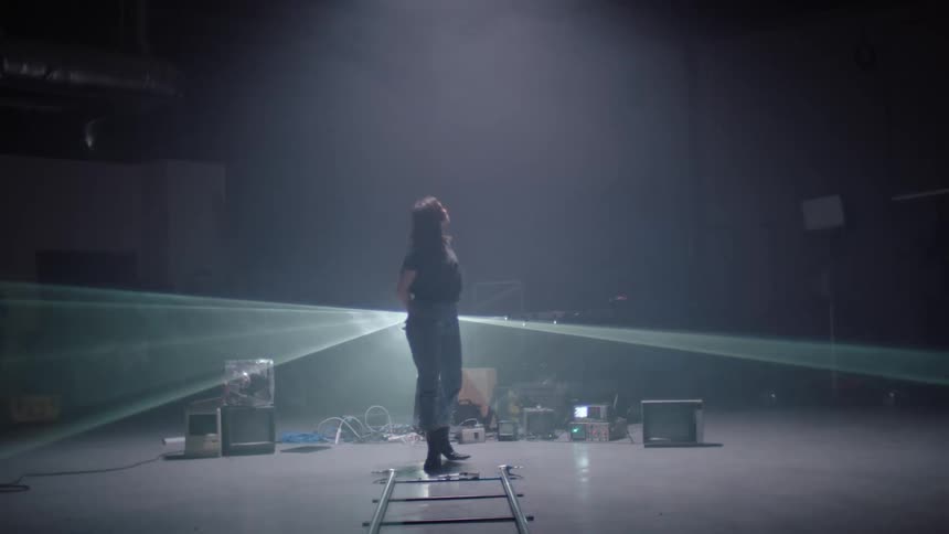A woman stands on a stage as lights flash