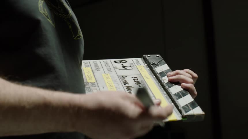 A man is writing on a clapperboard