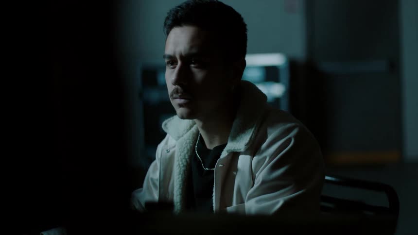 Sitting man studies monitors in large dimly lit room