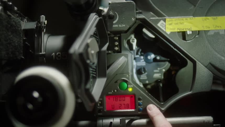 A finger presses a button to adjust speed or playback on filming equipment