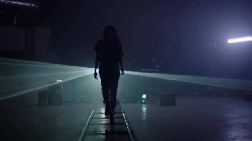 Woman silhouetted in dark room by laser lights and strobeswalks