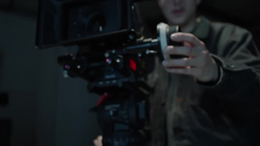 A man changes settings on a professional film camera