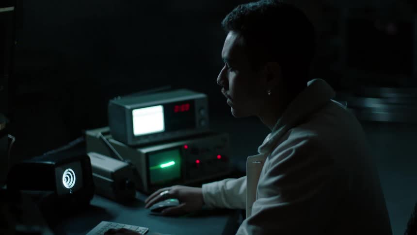 A man is sitting in the dark typing on a keyboard