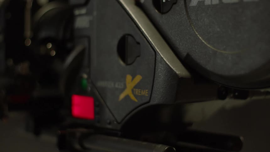A large video camera with lights display and multiple plugs and sockets