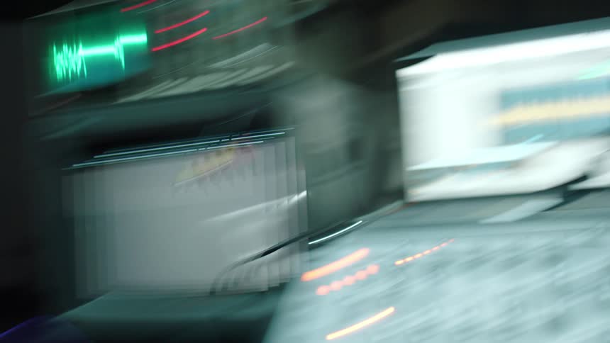 A control board with monitor screens and a camera blurs