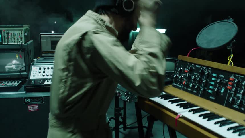 A musician plays on a keyboard and bangs a drum