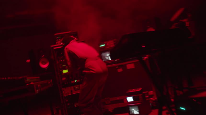 Man wearing headphones works on some technological devices as lights flash