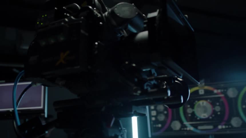 A film camera on a tripod sits in a dark room