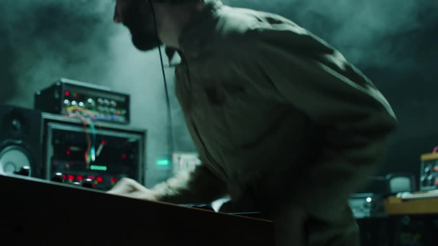 Musician plays keyboards surrounded by electronic equipment