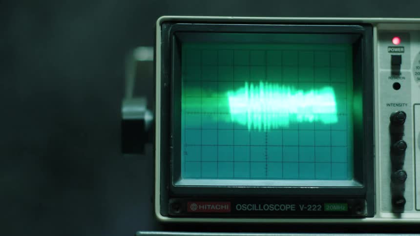 An oscilloscope displays a reading while smoke rises in the background
