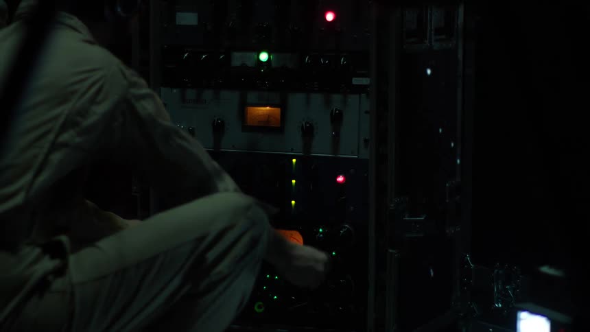 A white male turns dials on an old piece of machinery