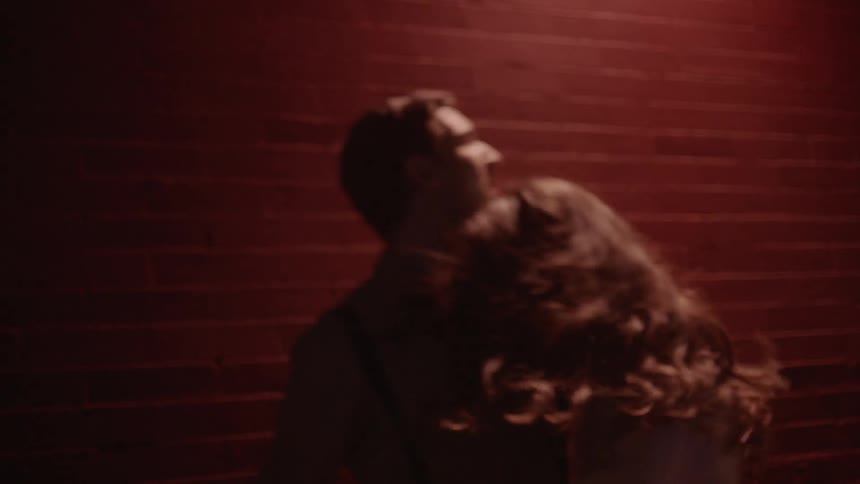 A man and woman run fearfully on dark city street