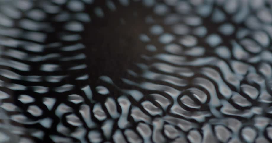 A moving pattern of light springs to life over a cup filled with a brown substance