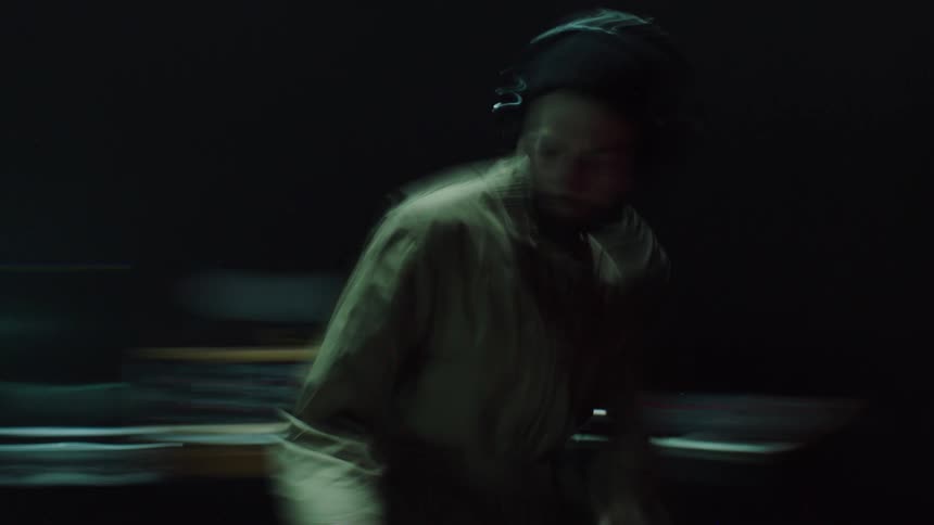 A man with headphones playing on a musical keyboard and djing