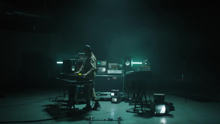 A man works on audio equipment as red lights flash