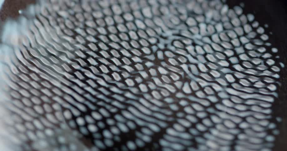 A vibrating pattern of light hovers over a cup with a brown substance in it