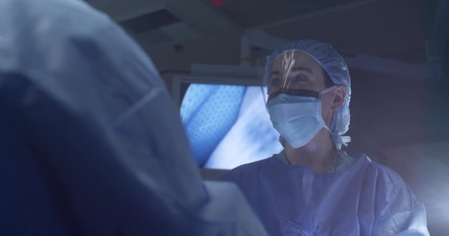 A surgeon talks and looks at a screen