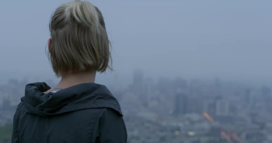 A woman looks out at the city skyline