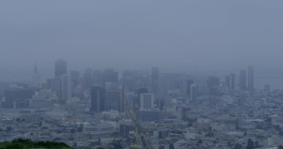 Fog obscures city skyline as lights of traffic lead to and from the city