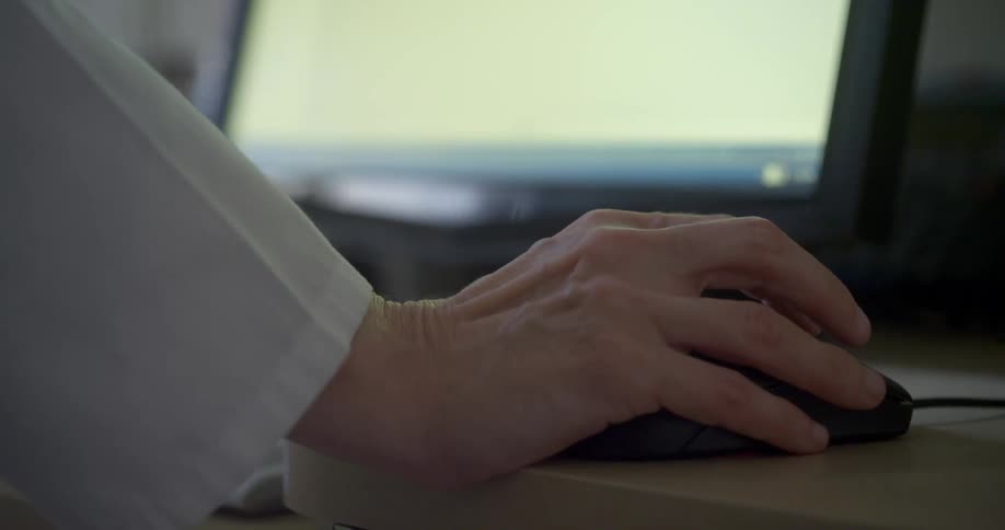 A person is using their mouse by the computer