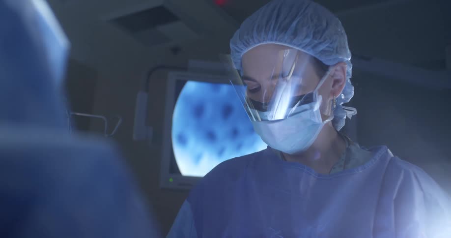 Female surgeon performing surgery near a television screen