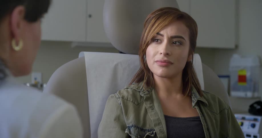 A woman nods while listening to her doctor during an exam