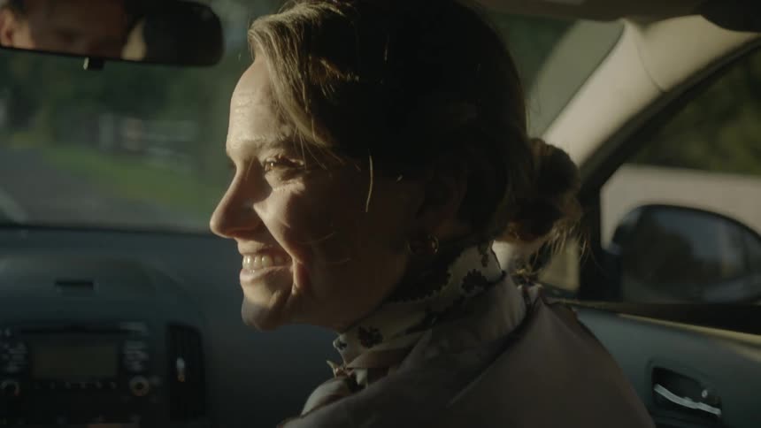 A woman smiles while riding as a passenger in a car